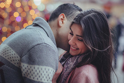 Dark haired couple embracing out front of The Hotel at Arundel Preserve