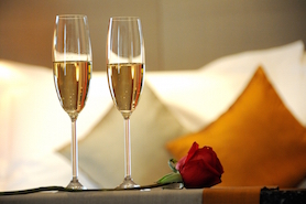 Two glasses of wine sitting on a bed with a rose at the Hotel at the Arundel Preserve