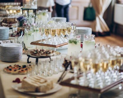stylish champagne glasses and food appetizers on table at wedding reception