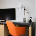 orange chair sitting at a desk with a TV